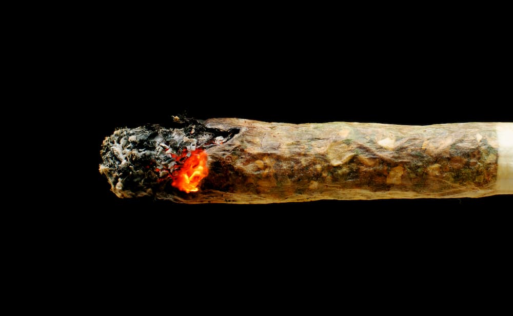 A lit joint close up as it burns with a black background